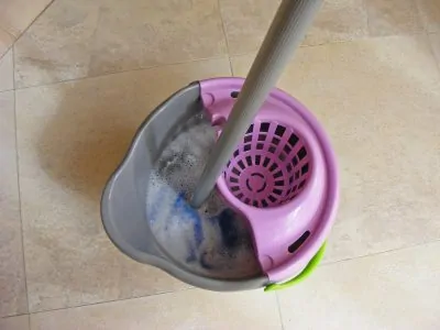 Blue mop inside grey and purple bucket on wet floor