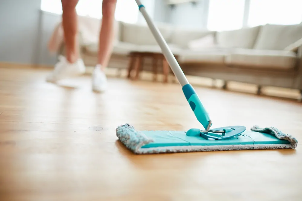 Woman cleaning living room floor with microfiber mop