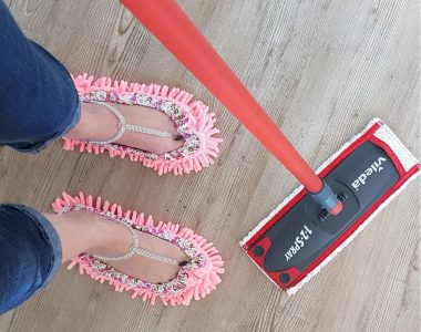 Woman wearing pink mop slippers and holding a mop