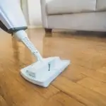 Cleaning the living room floor with a white steam mop
