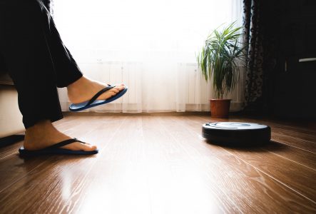 Person sitting on sofa while robot vacuum cleans the floor