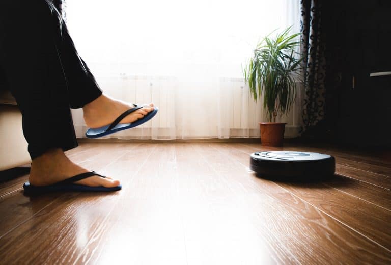 Person sitting on sofa while robot vacuum cleans the floor
