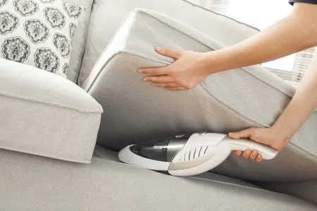 Cleaning the sofa with a cordless handheld vacuum