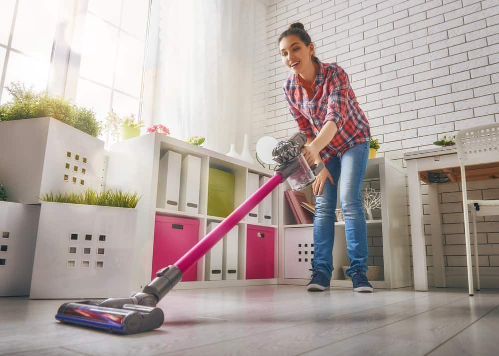 Woman cleans the floor with cordless stick vacuum