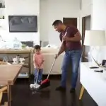 Father and son mopping their sitting room