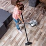 Young woman cleaning a laminate floor with a small vacuum
