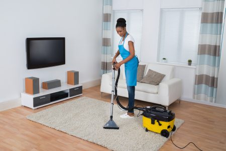 Woman cleaning the living room floor with a professiona vacuum