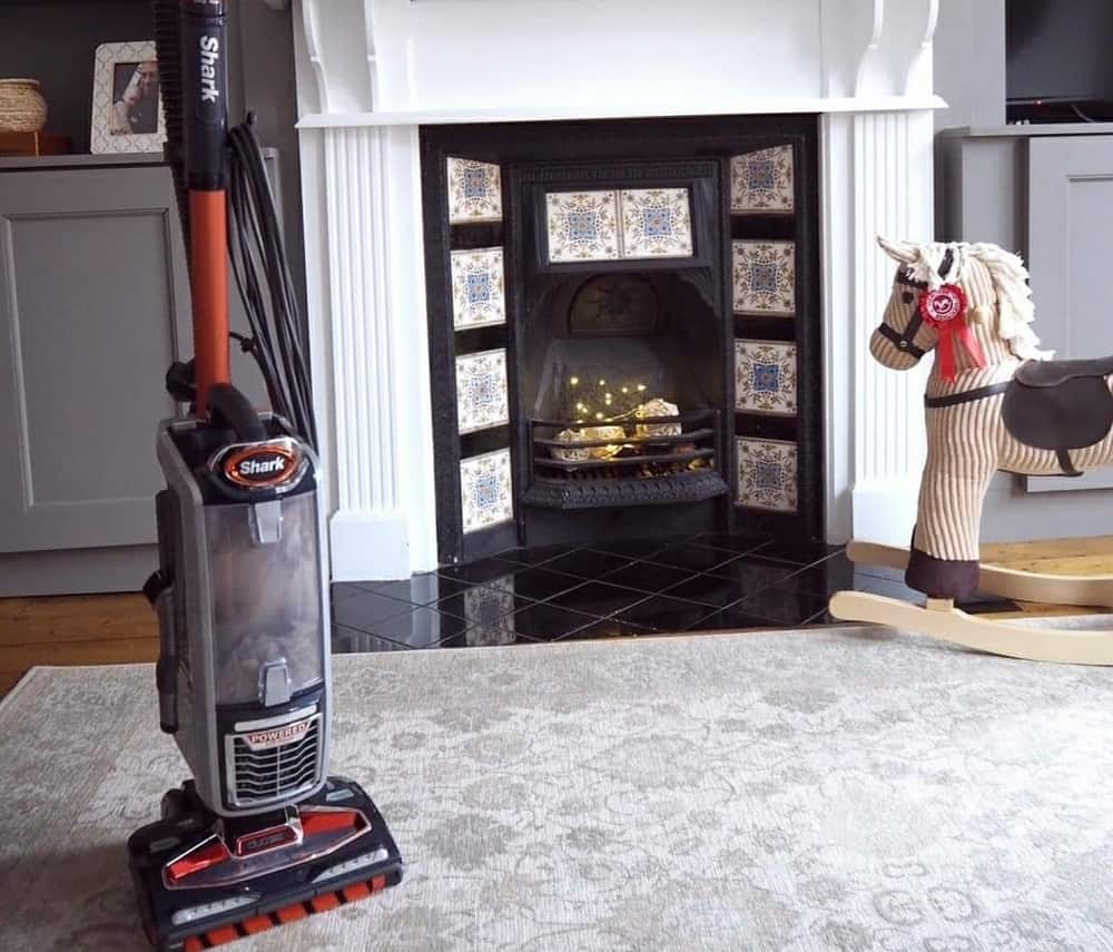 Cleaning the living room carpet with an upright vacuum