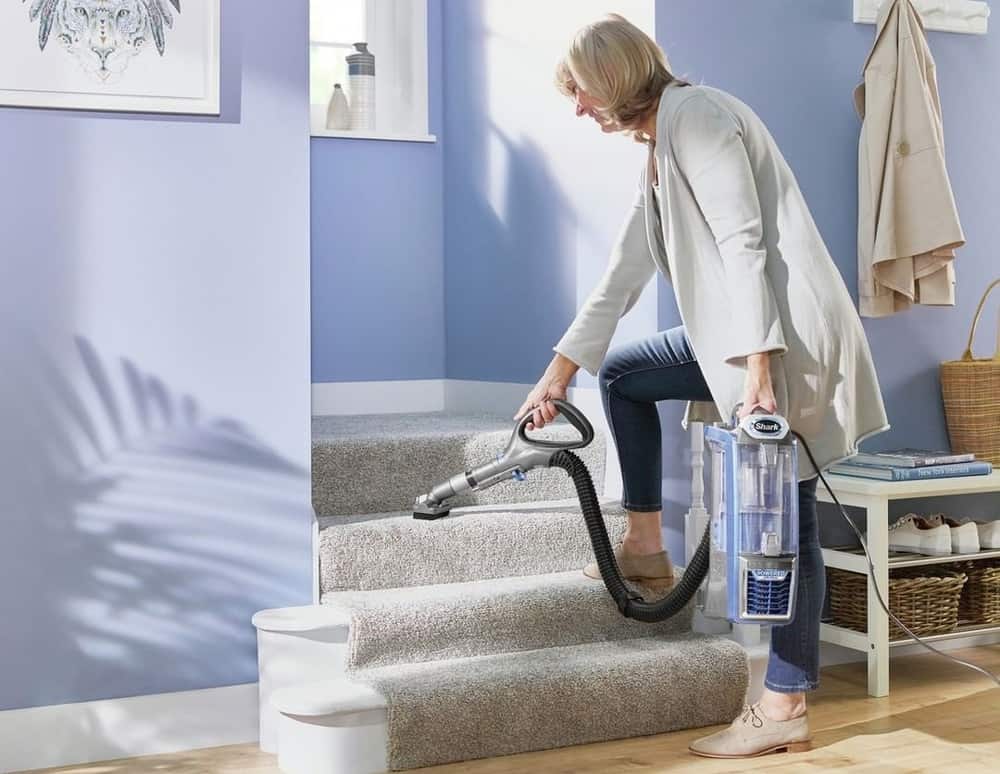 Woman cleaning the stairs with a vacuum
