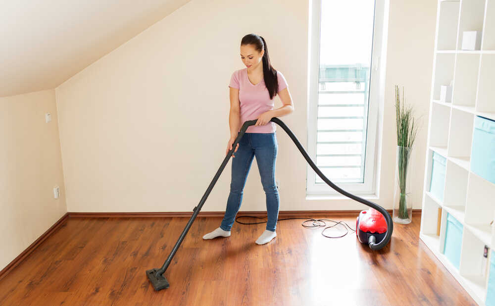 Woman vacuuming hard floor in her apartment