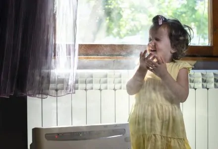 Little girl sneezing in a dusty room