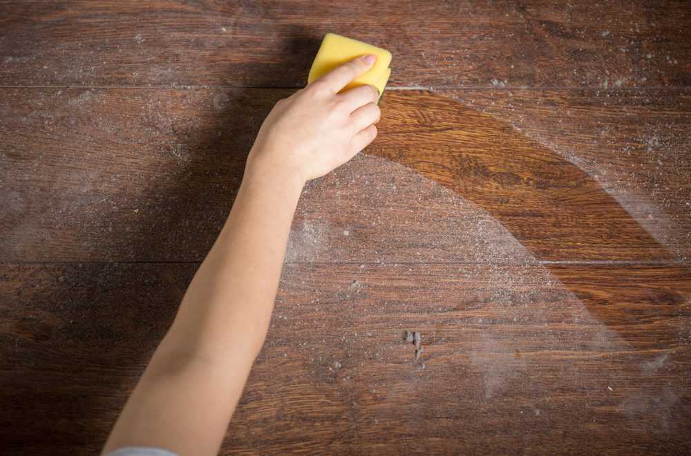 Woman cleaning dusty wood floor