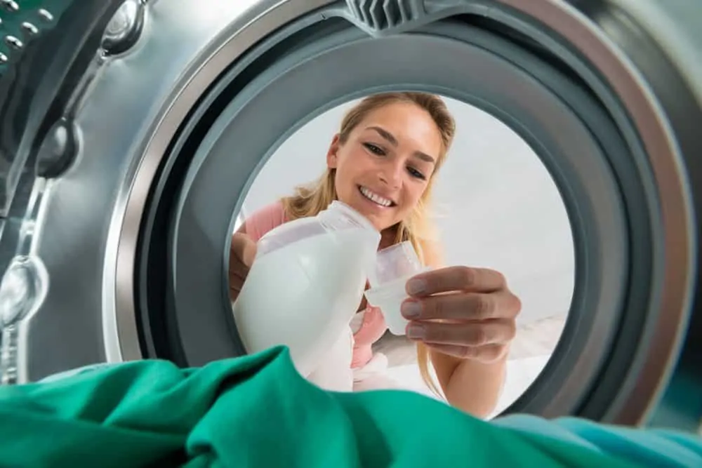 Woman pouring detergent for dark clothes in the washing machine