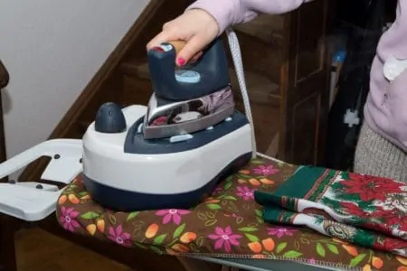 Woman ironing with a steam generator iron