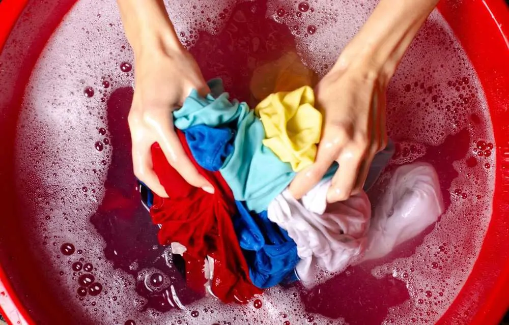 Woman hand washing clothes with a basin