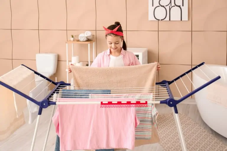 Woman hanging clothes on a clothes drying rack in the bathroom