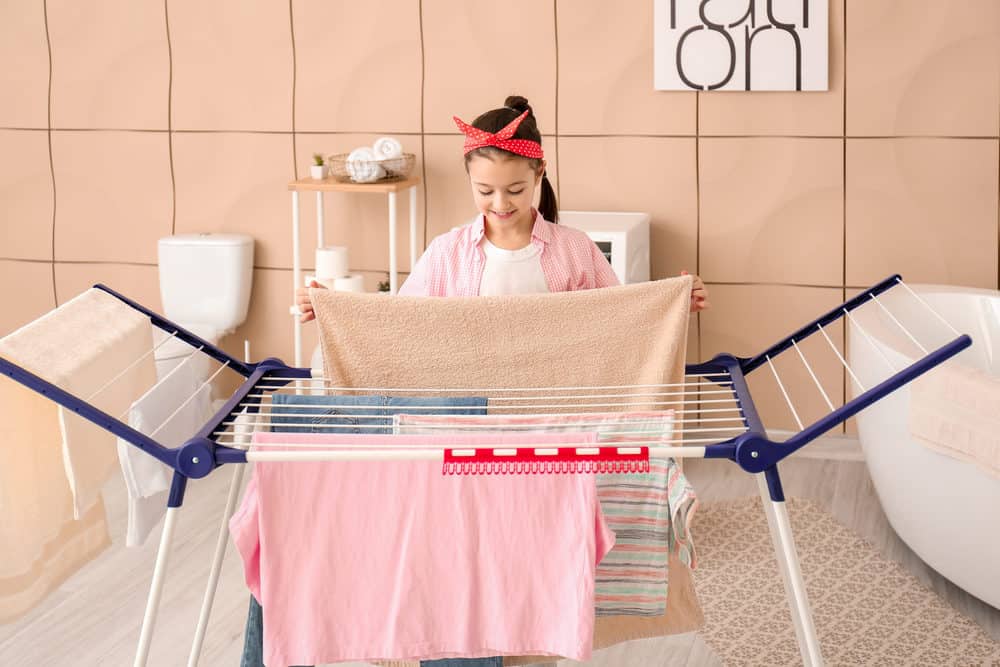 Woman hanging clothes on a clothes drying rack in the bathroom