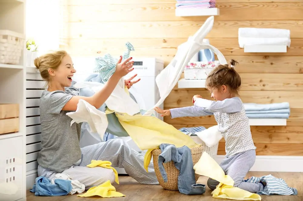 Mother and daughter having fun while doing laundry