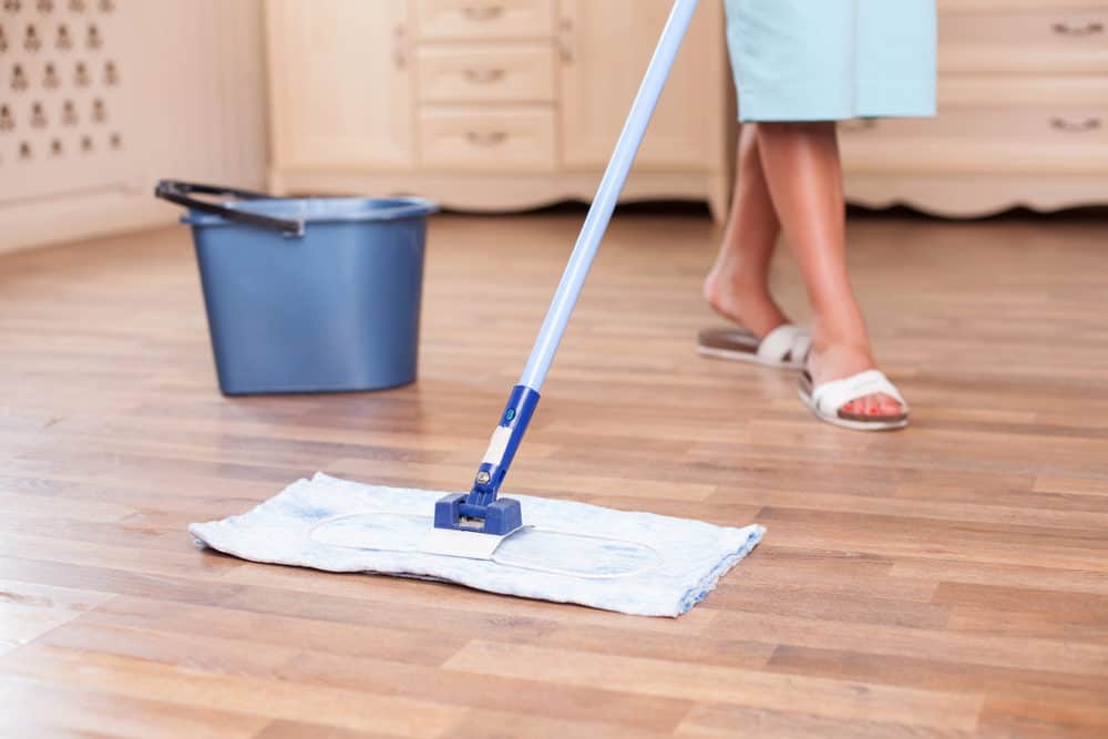 Woman mopping laminate floor with a flat mop