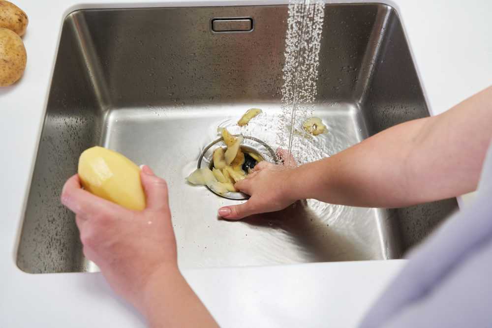 Food waste disposer machine in sink in modern kitchen