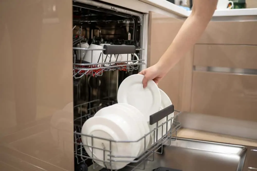 Woman loading dishwasher with plates
