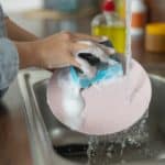 Woman washing a plate with liquid dish soap