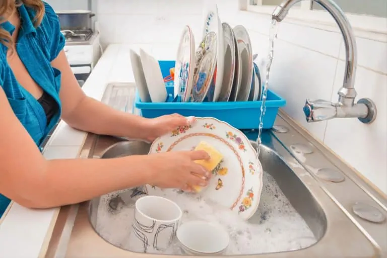Woman washing the dishes in the kitchen sink