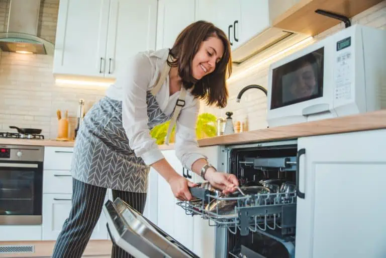 Smiling woman loading the dishwasher