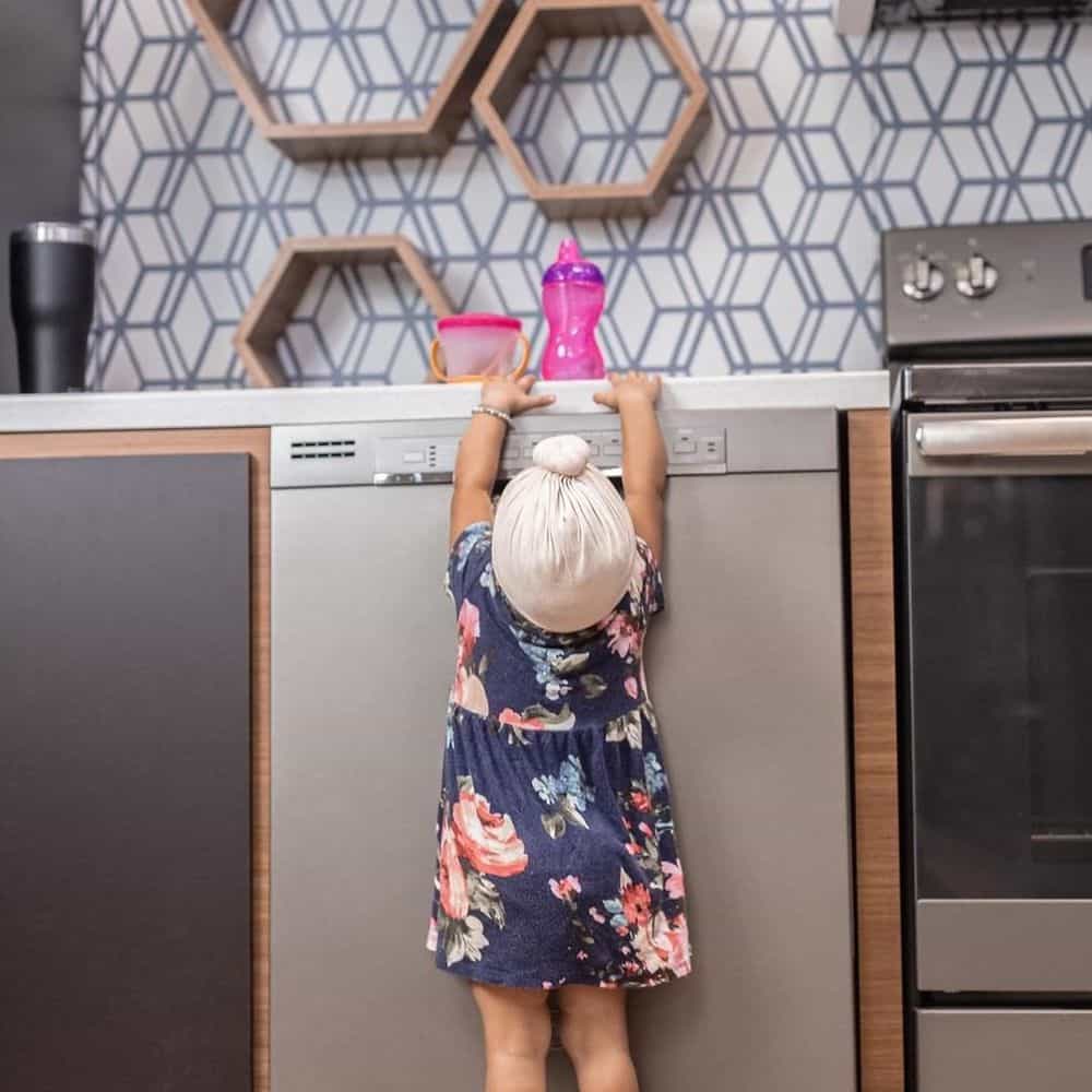 Girl reaching for glass above the dishwasher