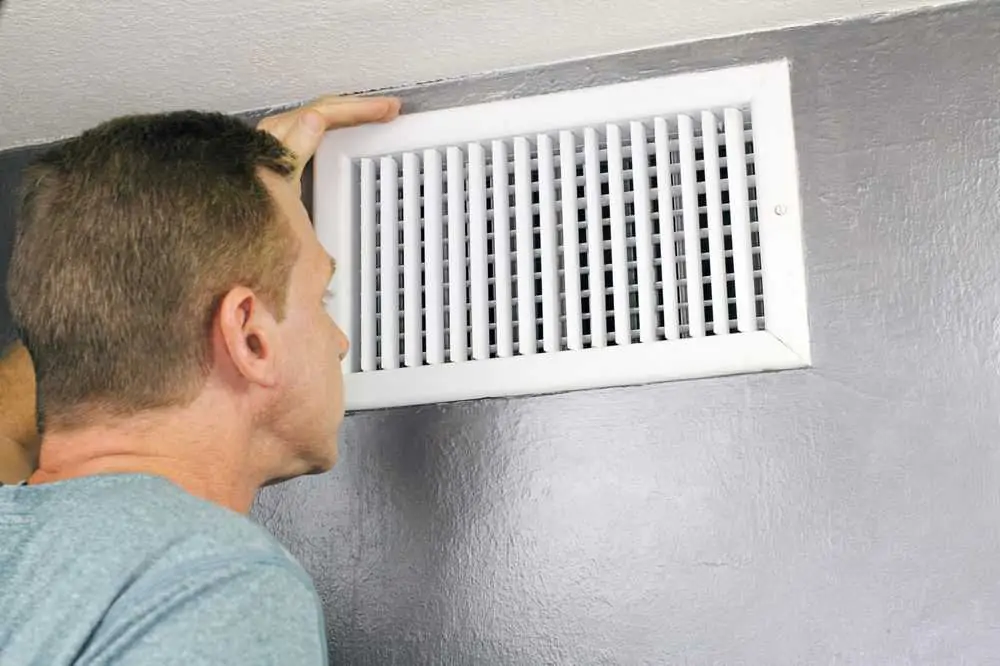 Man inspecting mold on air vent