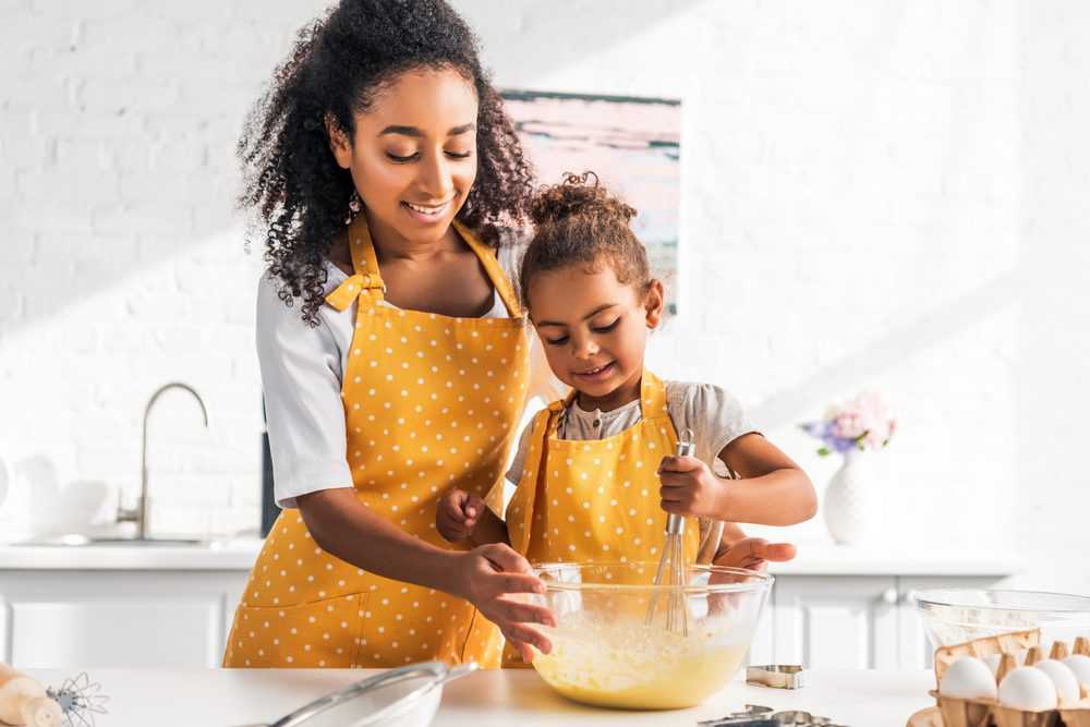 Beautiful mom and daughter baking together wearing matching aprons