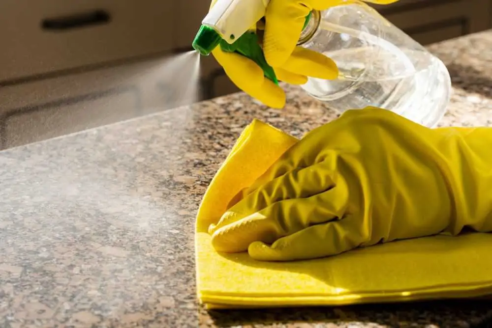 Man cleaning kitchen granite counter with cleaning solution
