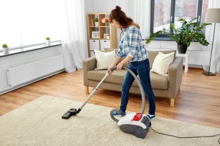Woman vacuuming carpet and hardwood floor