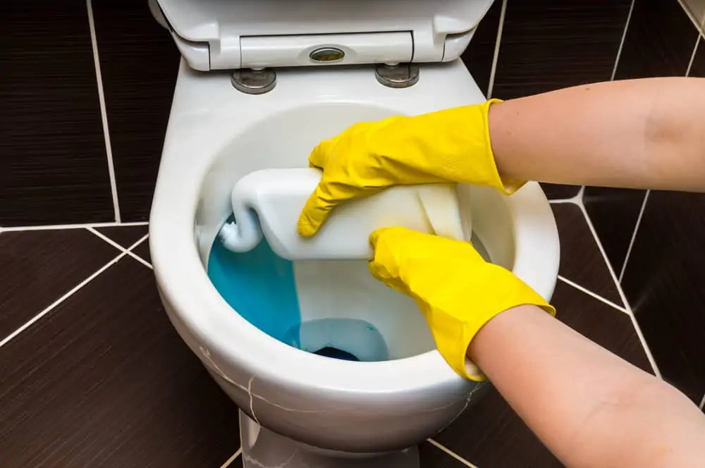 Woman cleaning toilet bowl using detergent
