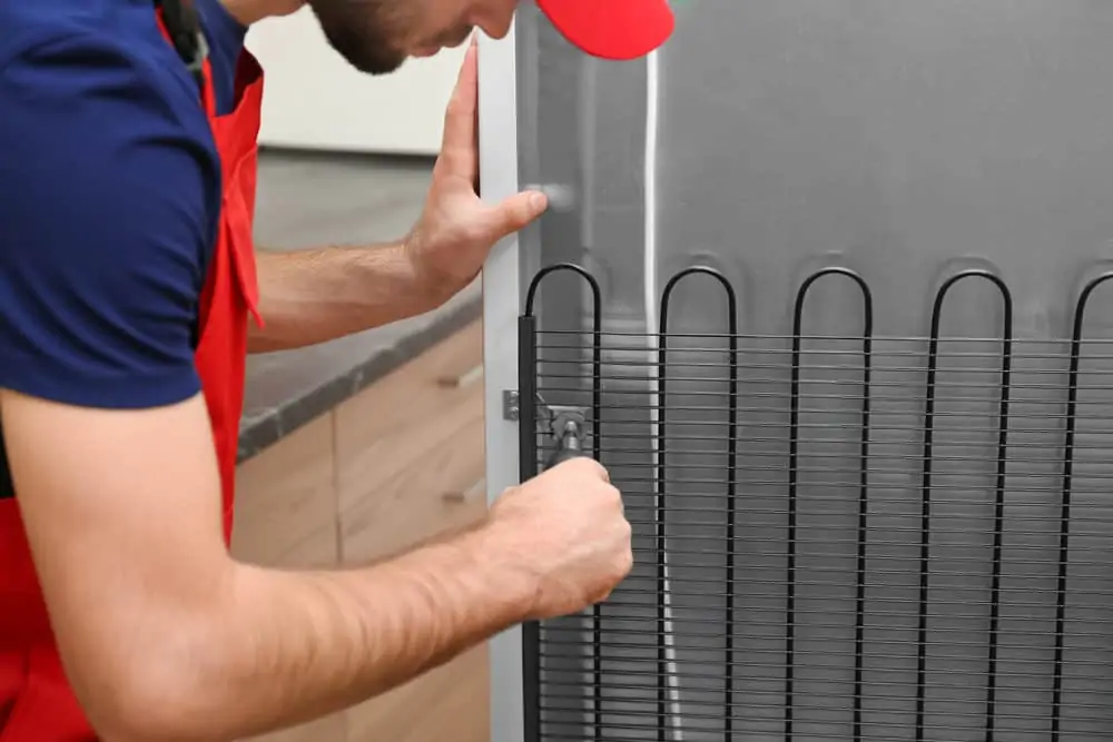 Male technician repairing refrigerator indoors