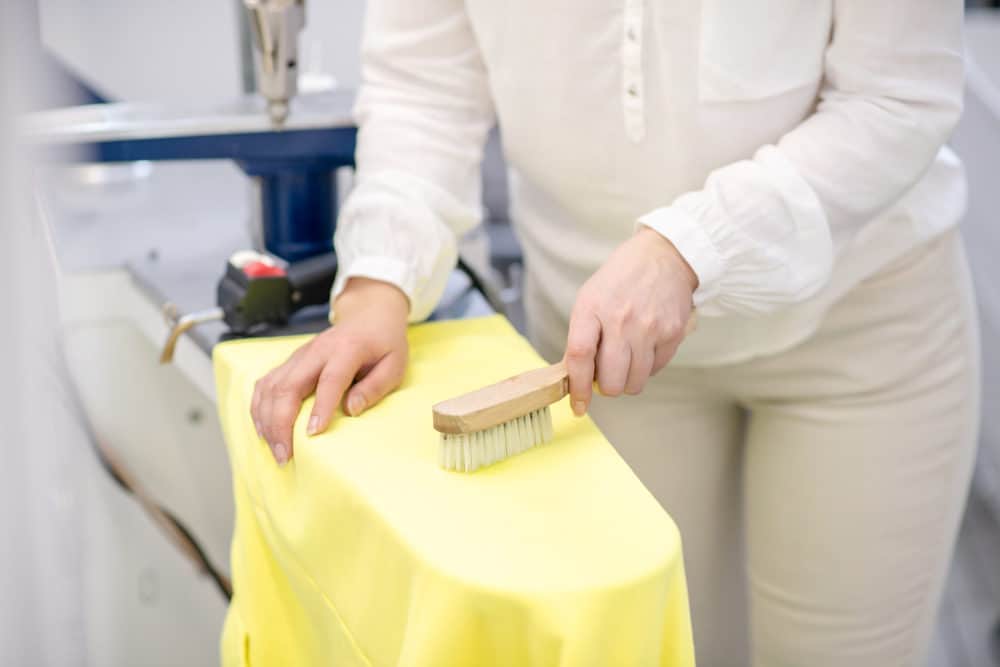 Woman brushing yellow cloth in dry cleaning