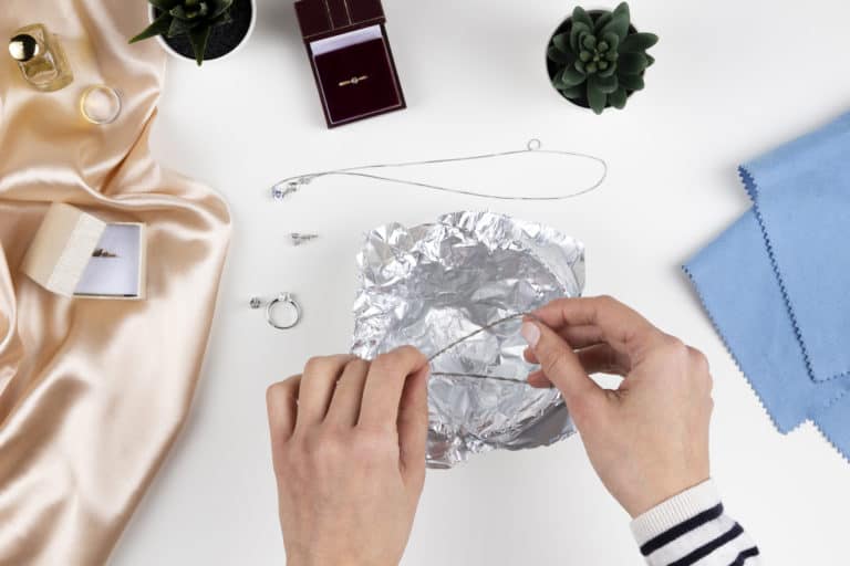 Woman cleaning silver jewelry with homemade jewelry cleaner at home