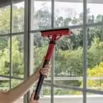 Woman cleaning window glass with steam mop