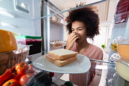 Woman noticing bad smell from fridge