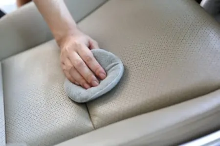 Woman hand cleaning leather car seat