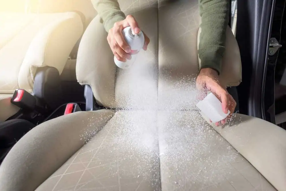 Woman cleaning the car seat with anti-odor spray