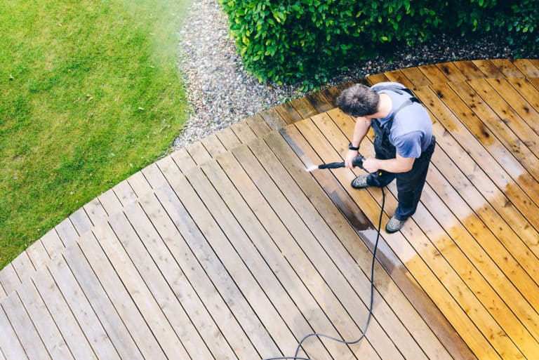 Man pressure washing his deck