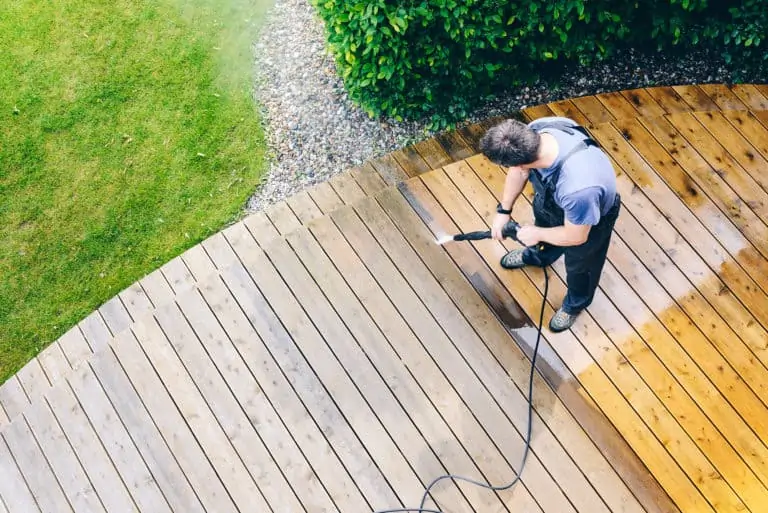 Man pressure washing his deck