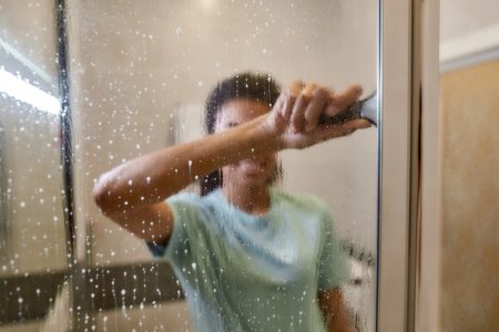 Woman cleaning hard water stains from shower door