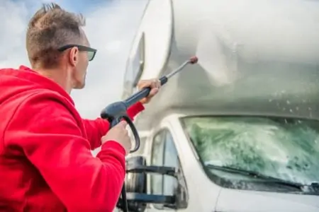 Man cleaning RV with power washer