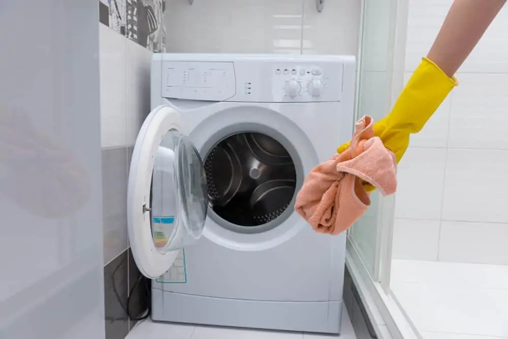 Woman drying out washing machine after wiping with cloth