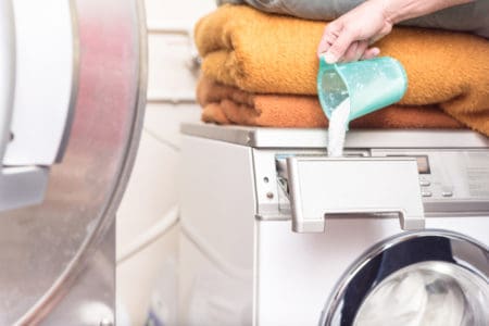 Hand pouring powder detergent into washing machine