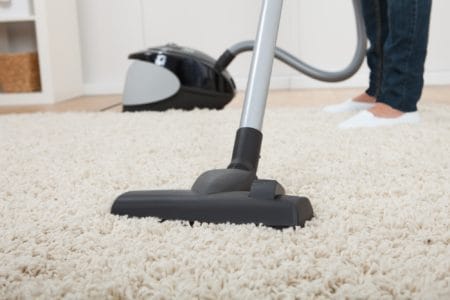 Woman cleaning wool rug with vacuum