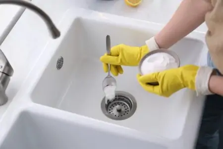 Woman putting baking soda into sink drain