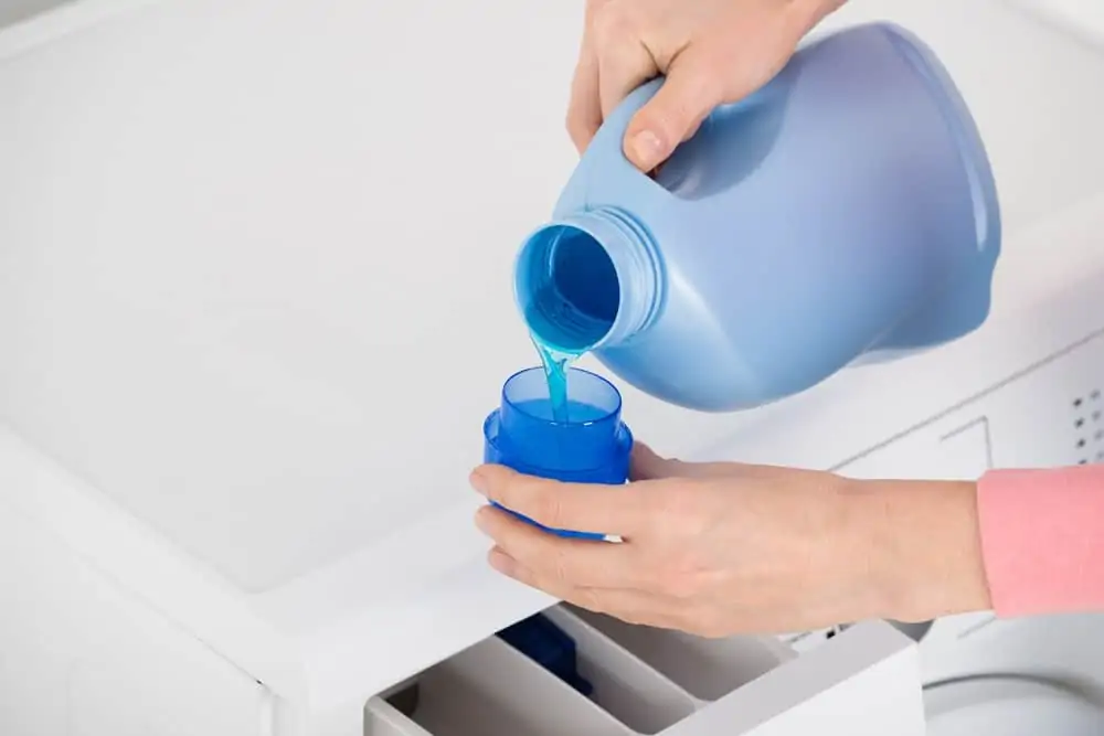 Female hand pouring laundry detergent in the blue bottle cap